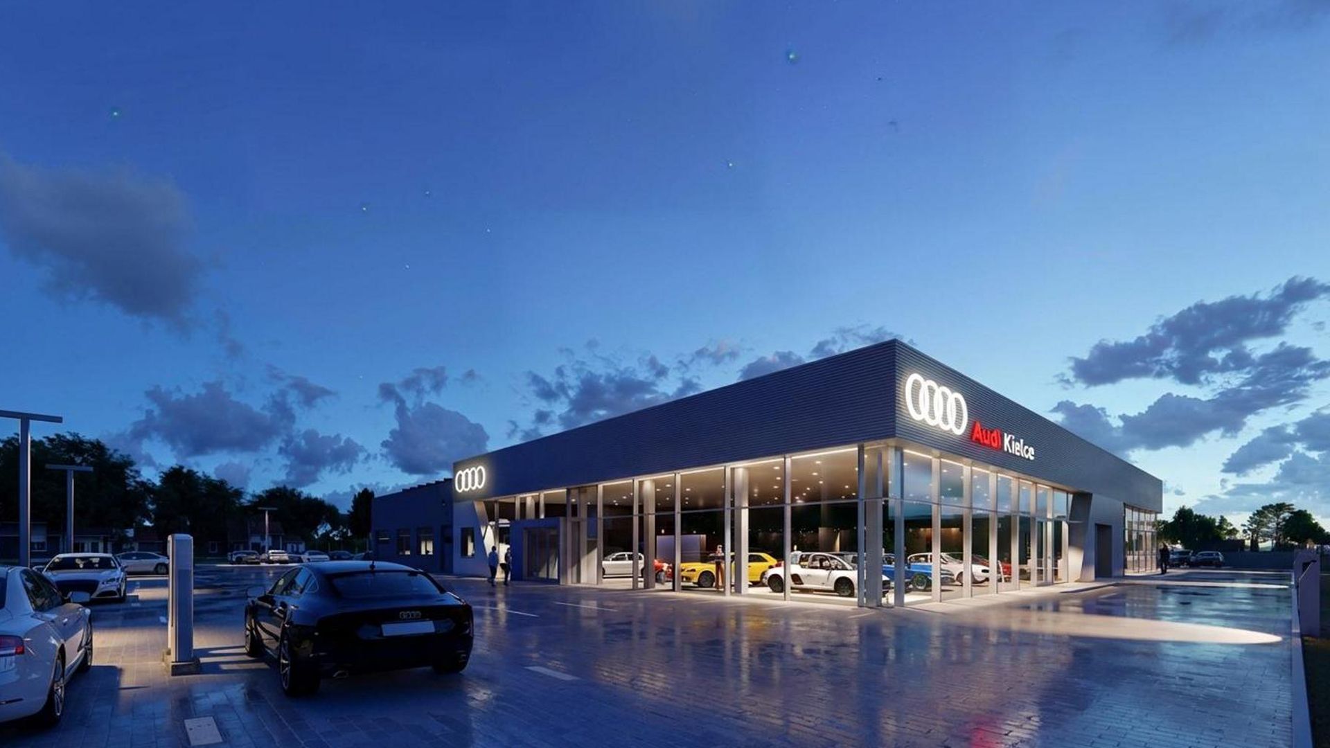 A modern Audi showroom illuminated at dusk, with a sleek glass façade showcasing various Audi models inside. The glowing Audi logo and red signage stand out against the deep blue evening sky. Luxury vehicles are parked in the foreground, with ambient lighting and clean pavement enhancing the upscale atmosphere of the dealership. Scattered clouds and fading daylight complete the twilight setting.