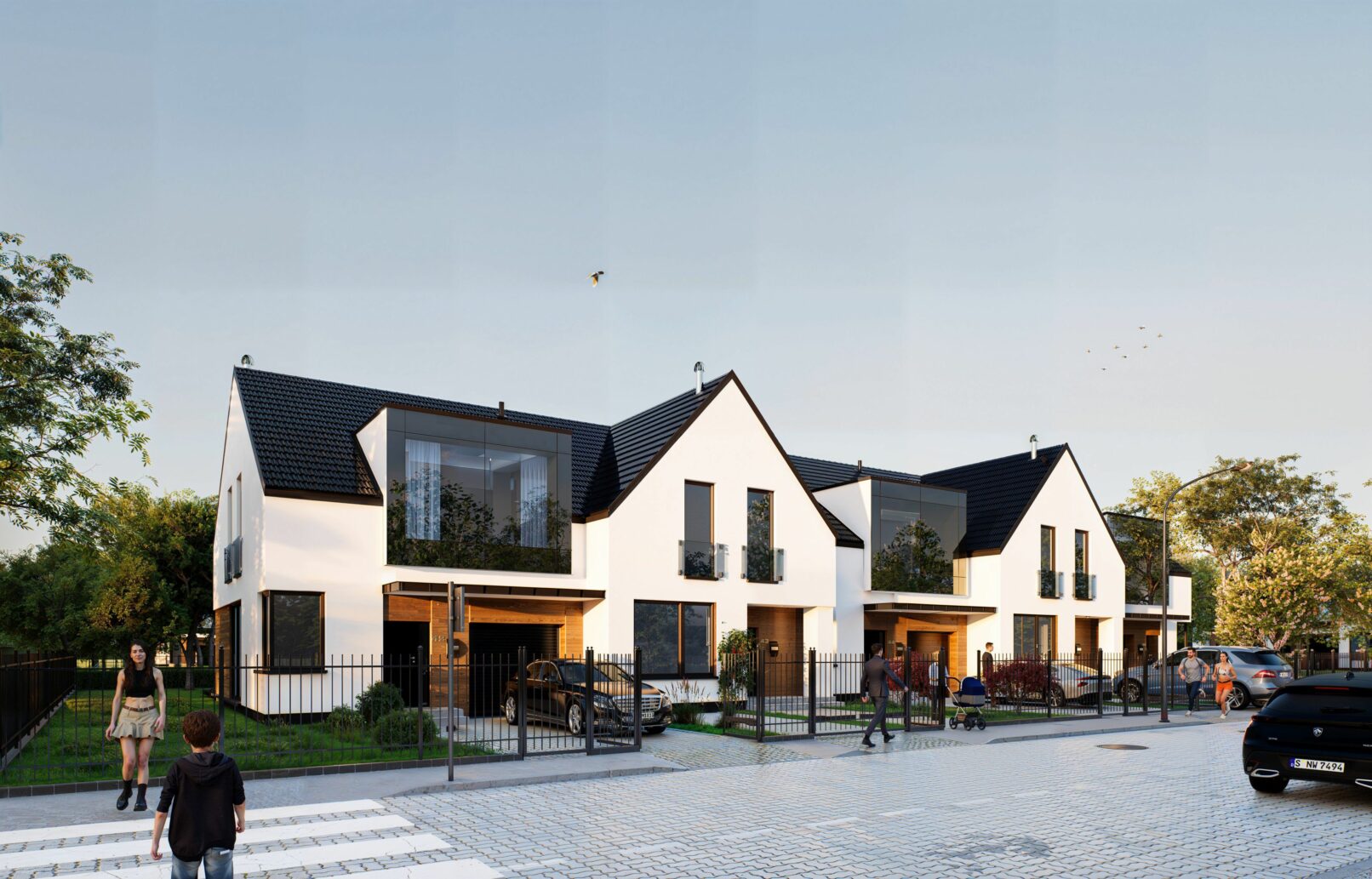 A modern suburban housing development featuring white gable-roofed buildings with dark accents, large windows, and fenced front gardens. The visuals capture different angles of the row houses set against a soft blue sky and cobblestone street with people walking, cars parked, and lush greenery enhancing the residential atmosphere.