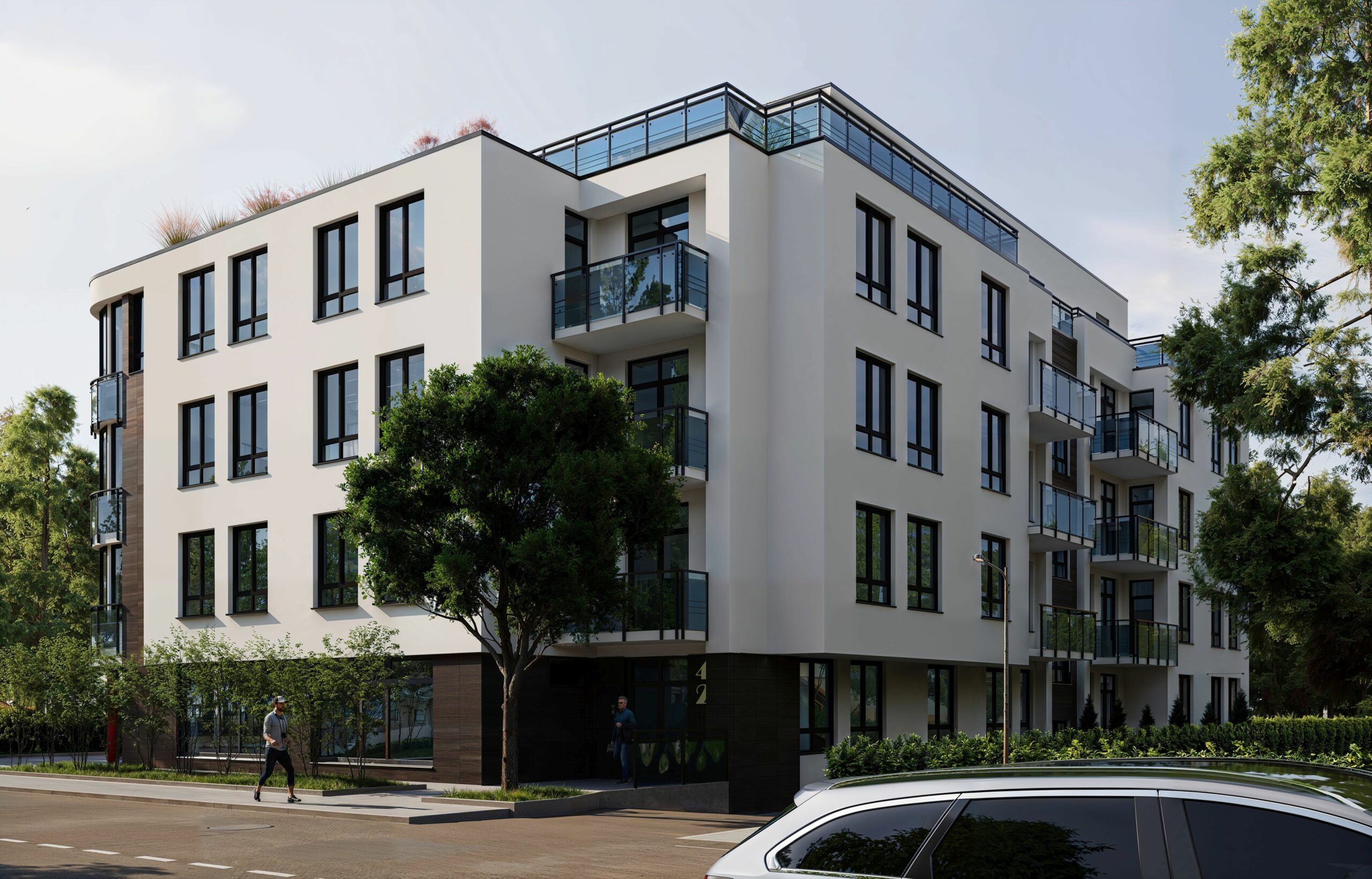 Corner view of Krancowa Residences showcasing modern façade with clean lines, glass balconies and lush greenery.